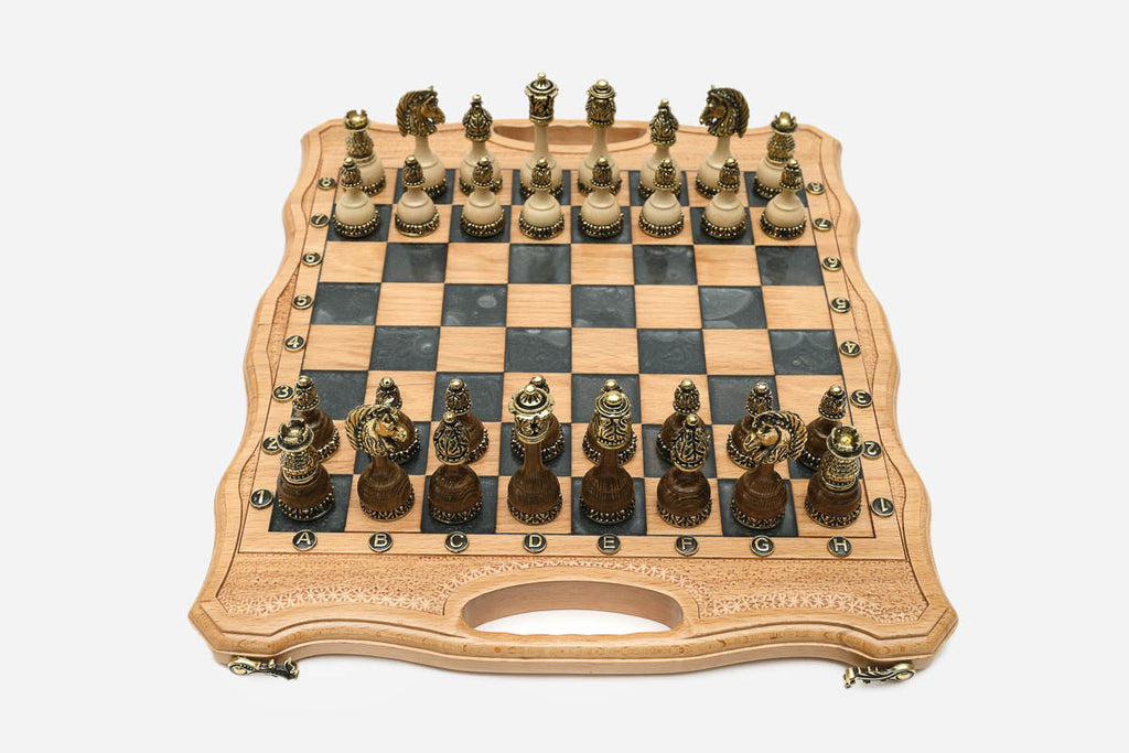 Folding chess board in pale wood with gray marbled epoxy squares and ornate bronze figural pieces set up for play