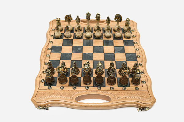 Folding chess board in pale wood with gray marbled epoxy squares and ornate bronze figural pieces set up for play