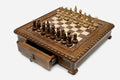 Carved chess set with wood pieces set up and the front drawer open, angled view