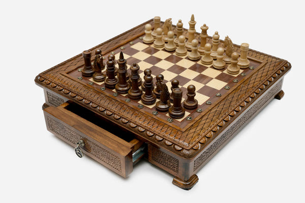 Carved chess set with wood pieces set up and the front drawer open, angled view