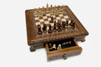 Carved chess set with wood pieces and the drawer open showing spare pieces, angled view