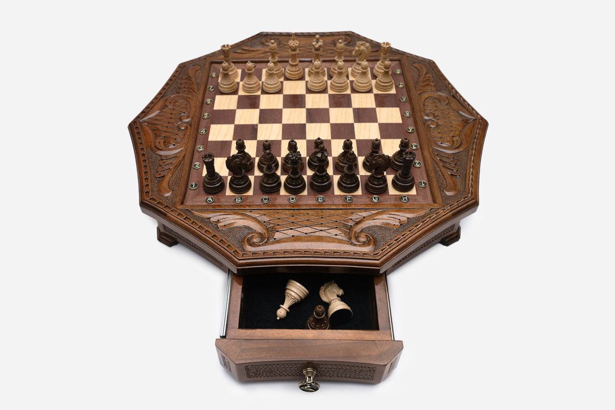 Octagonal chess set with the storage drawer open showing the carved wooden pieces inside