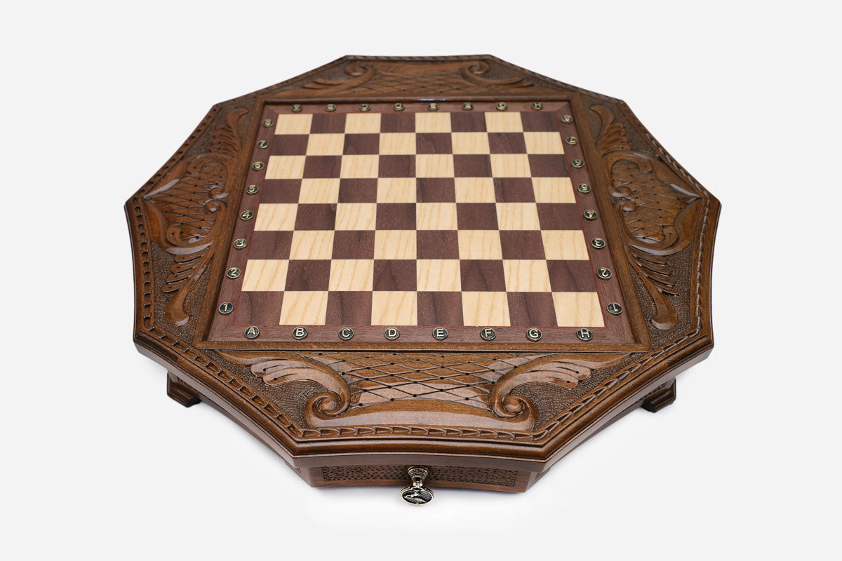 Top-down view of the octagonal honey-walnut chess board with brass coordinate markers and carved lattice frame