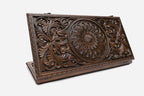 The board shown closed, revealing the deep-relief central ornament and scrollwork