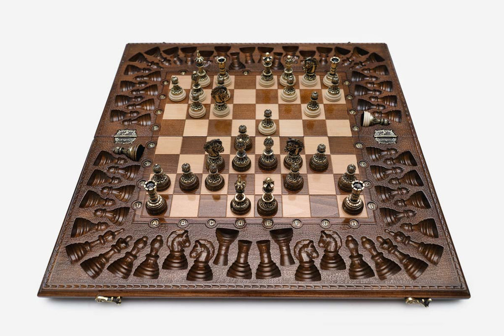 Close-up of the ornate bronze chess pieces with sculpted crowns and pale bases
