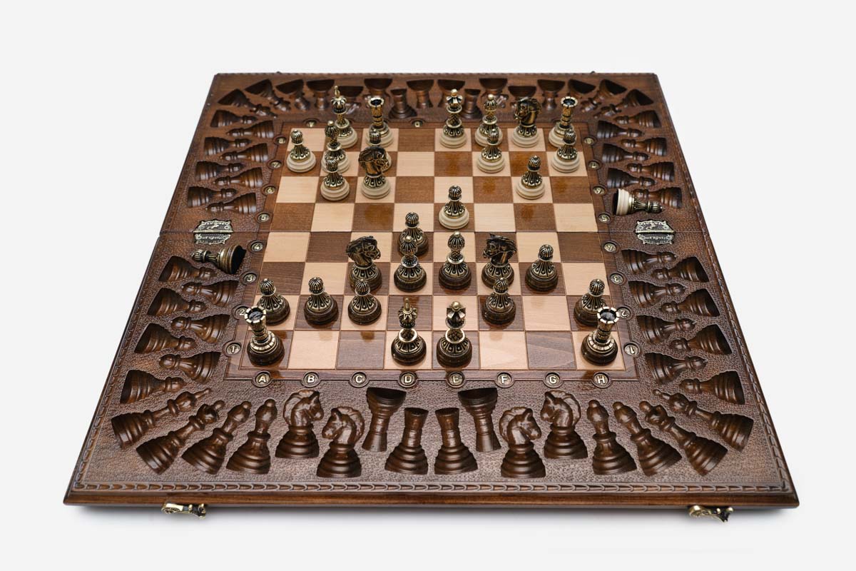 Close-up of the ornate bronze chess pieces with sculpted crowns and pale bases