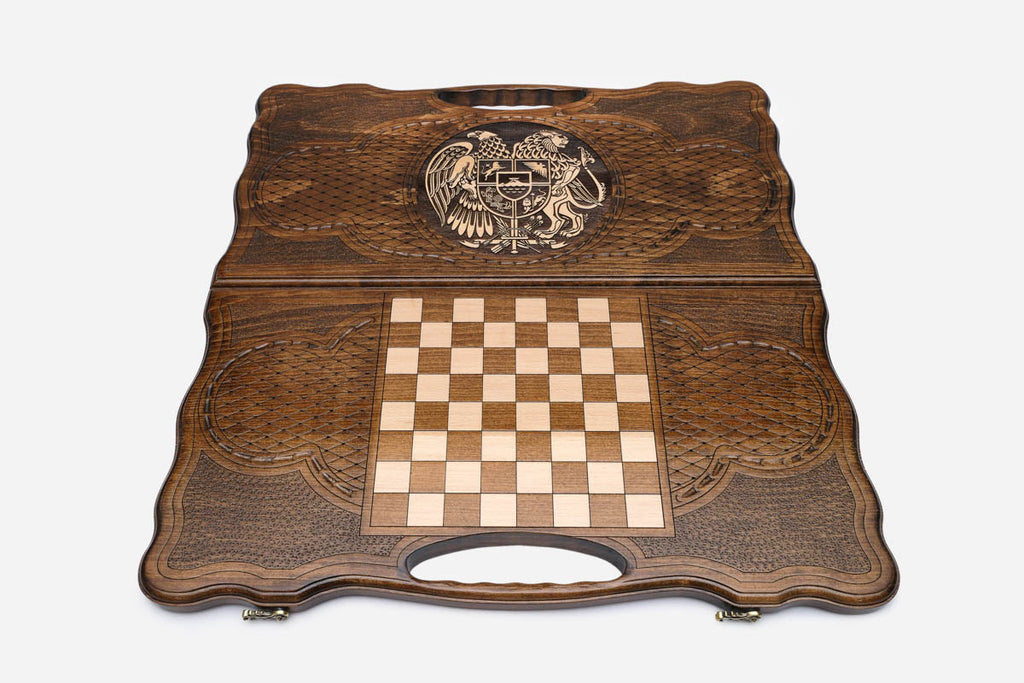 Angled view of the handmade Armenian backgammon set showing the bronze emblem on the carved lid