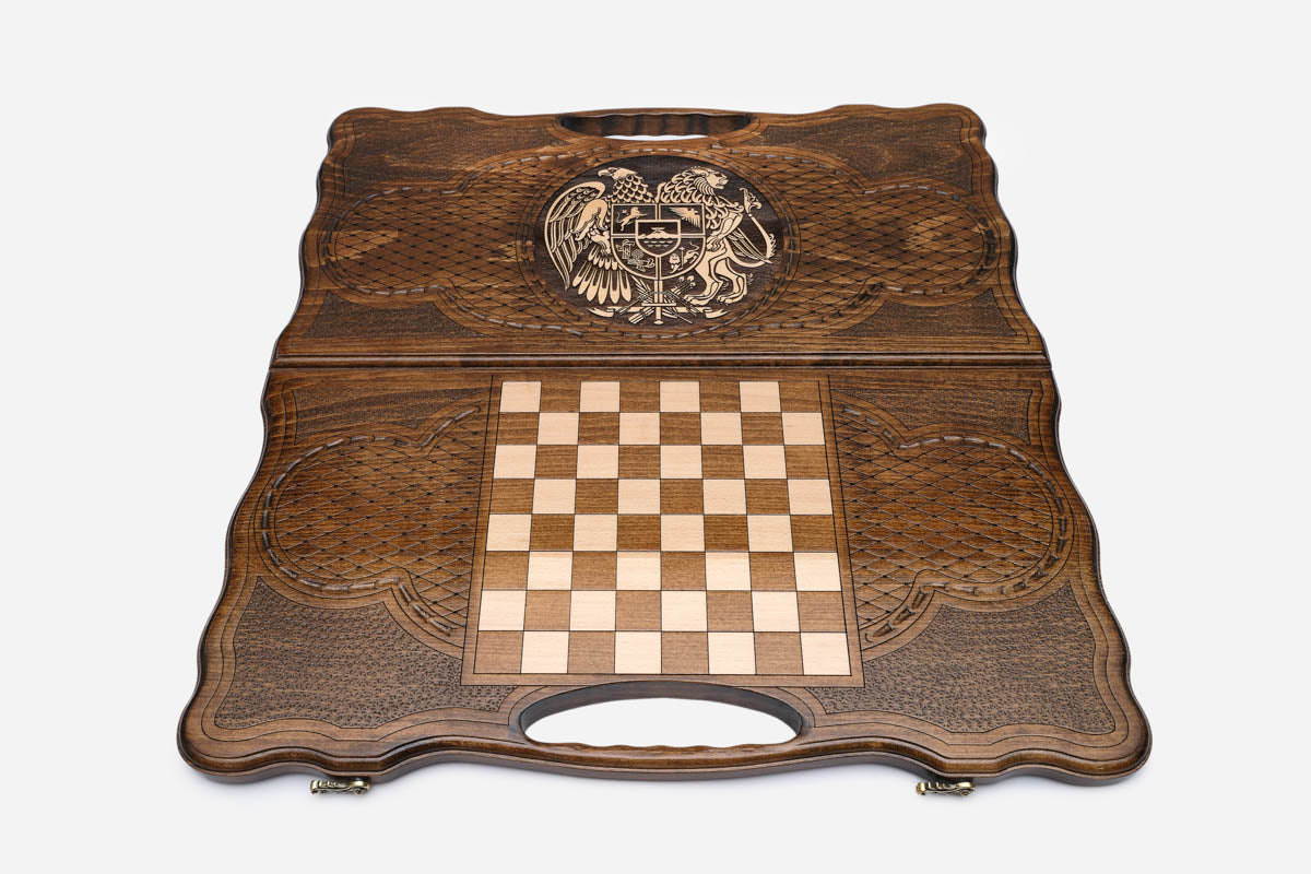 Angled view of the handmade Armenian backgammon set showing the bronze emblem on the carved lid