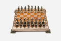 Chess board in pale wood with orange epoxy squares, brass corner brackets and figural bronze Greek-warrior pieces set up for play