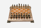 Chess board in pale wood with orange epoxy squares, brass corner brackets and figural bronze Greek-warrior pieces set up for play
