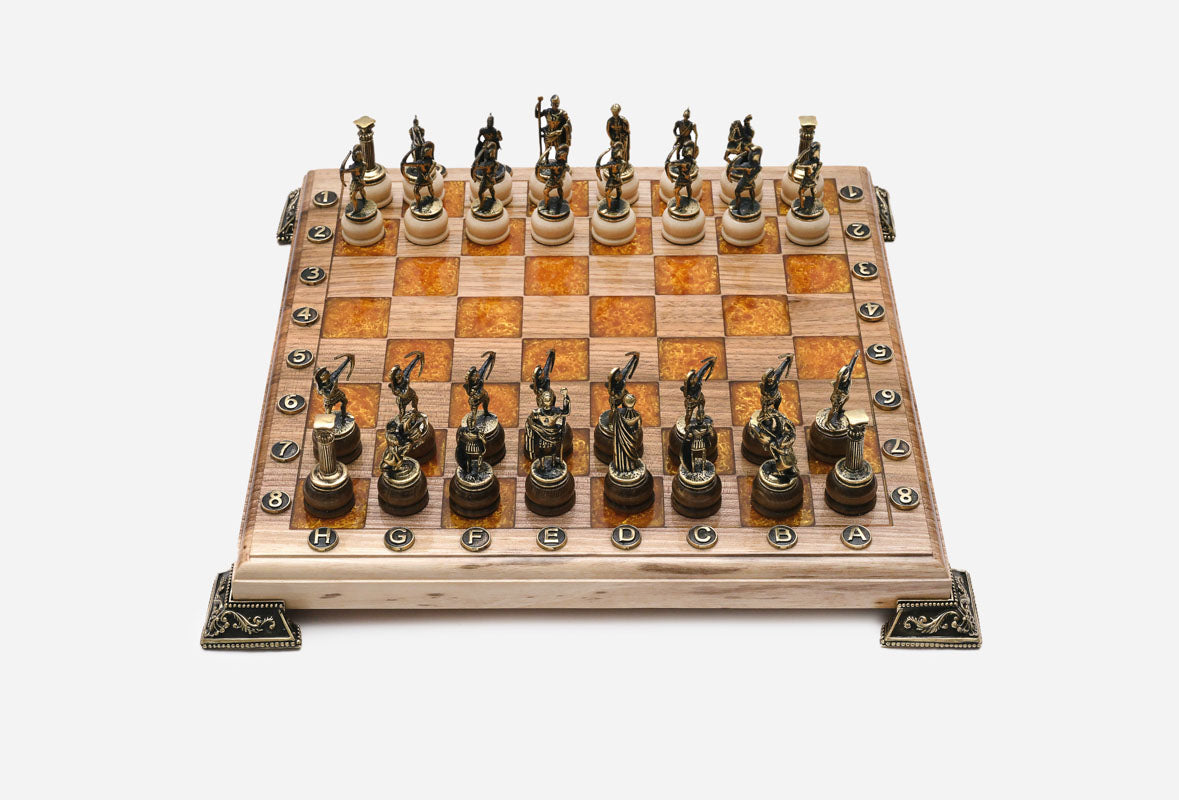 Chess board in pale wood with orange epoxy squares, brass corner brackets and figural bronze Greek-warrior pieces set up for play