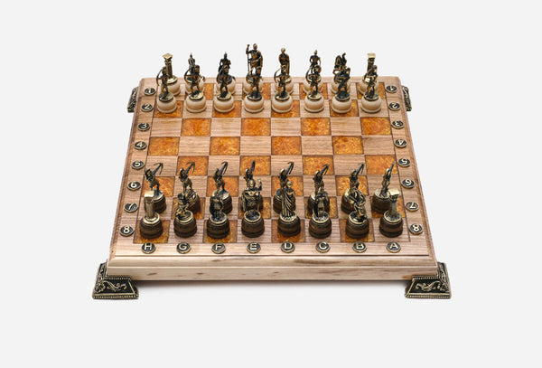 Chess board in pale wood with orange epoxy squares, brass corner brackets and figural bronze Greek-warrior pieces set up for play