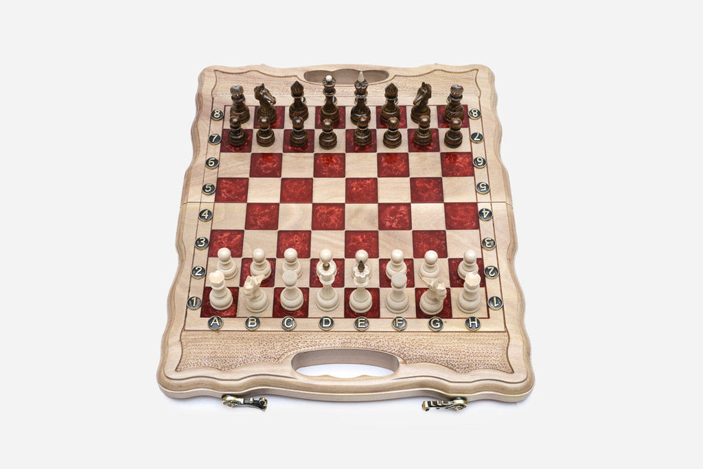 Compact folding chess board in pale wood with red epoxy squares and wooden pieces set up for play