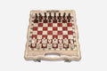 Compact folding chess board in pale wood with red epoxy squares and wooden pieces set up for play