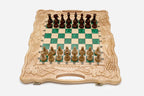 Folding chess board in pale wood with green epoxy squares, carved grape-vine borders and wooden pieces set up for play