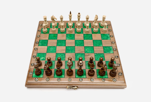 Compact folding walnut chess board with green epoxy squares and wooden pieces set up for play
