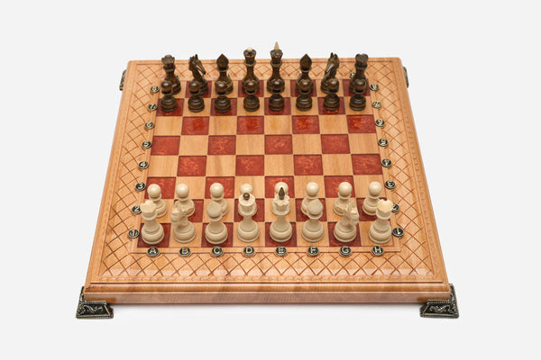 Folding chess board in pale wood with red epoxy squares, brass corner brackets and wooden pieces set up for play