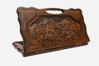 Hand-carved wooden backgammon board with a hunter and bear scene and a cut-out carry handle, propped open