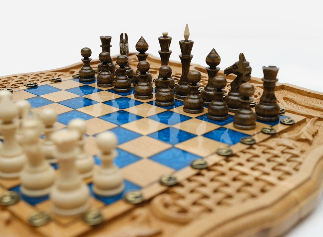 Angled view of the folding blue epoxy chess board with its carved woven ornament panels