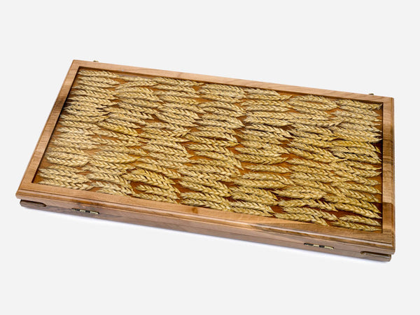 Folding walnut backgammon board with real wheat ears cast in clear amber epoxy in a herringbone pattern, shown closed at an angle