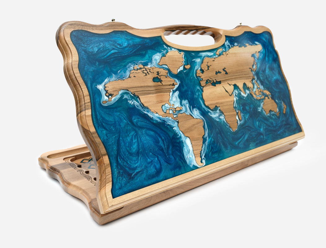 Folding backgammon board with a world map - wooden continents set in swirling blue and teal epoxy oceans - standing open with a carved carry handle