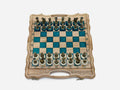 Luxury turquoise epoxy chess set opened flat with ornate bronze pieces on cream bases