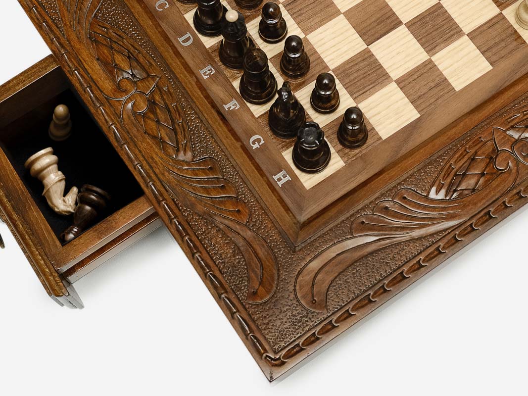 Close-up of a side drawer open with wood chess pieces stored inside