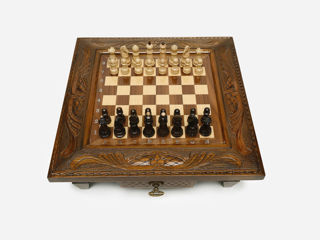 Carved chess set with wood pieces set up, angled view