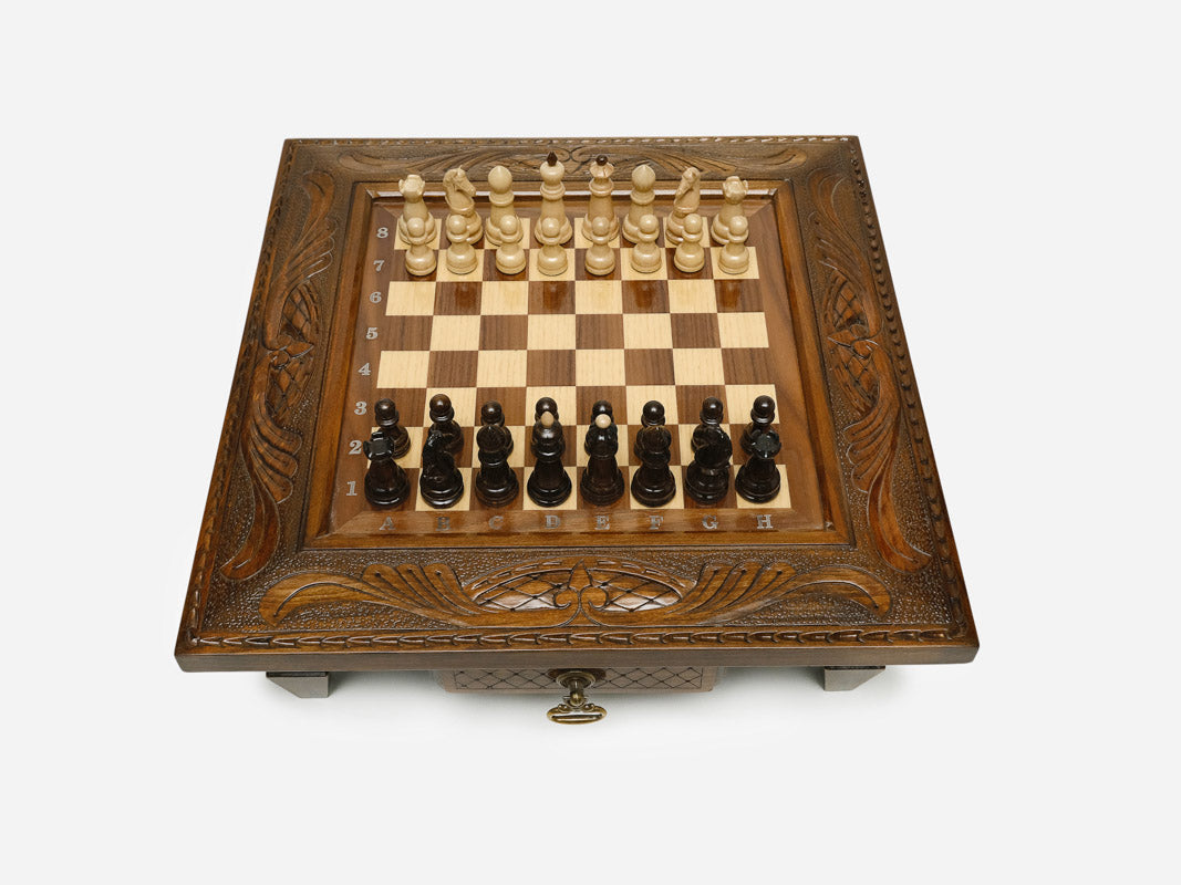 Carved chess set with wood pieces set up, angled view