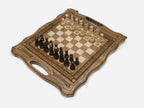 Overhead view of the carved chess board with the full set of light and dark wooden pieces