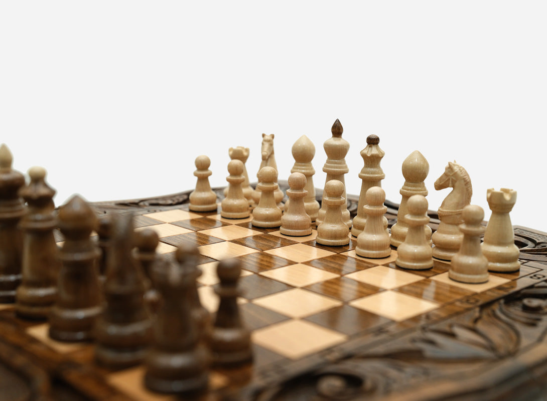 Overhead view of the carved chess board with the full set of pieces in starting position