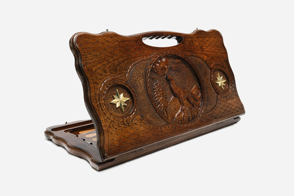 Carved wooden backgammon board with a wolf, two bronze stars and a cut-out carry handle, propped open