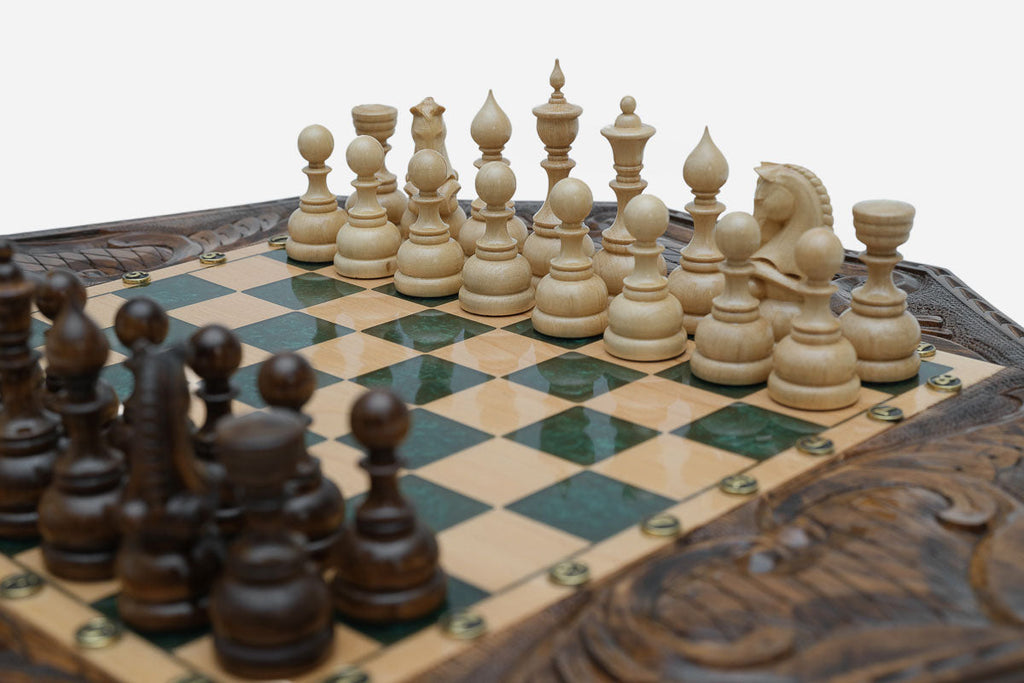Close-up of the dark wooden chess pieces standing on the green epoxy board