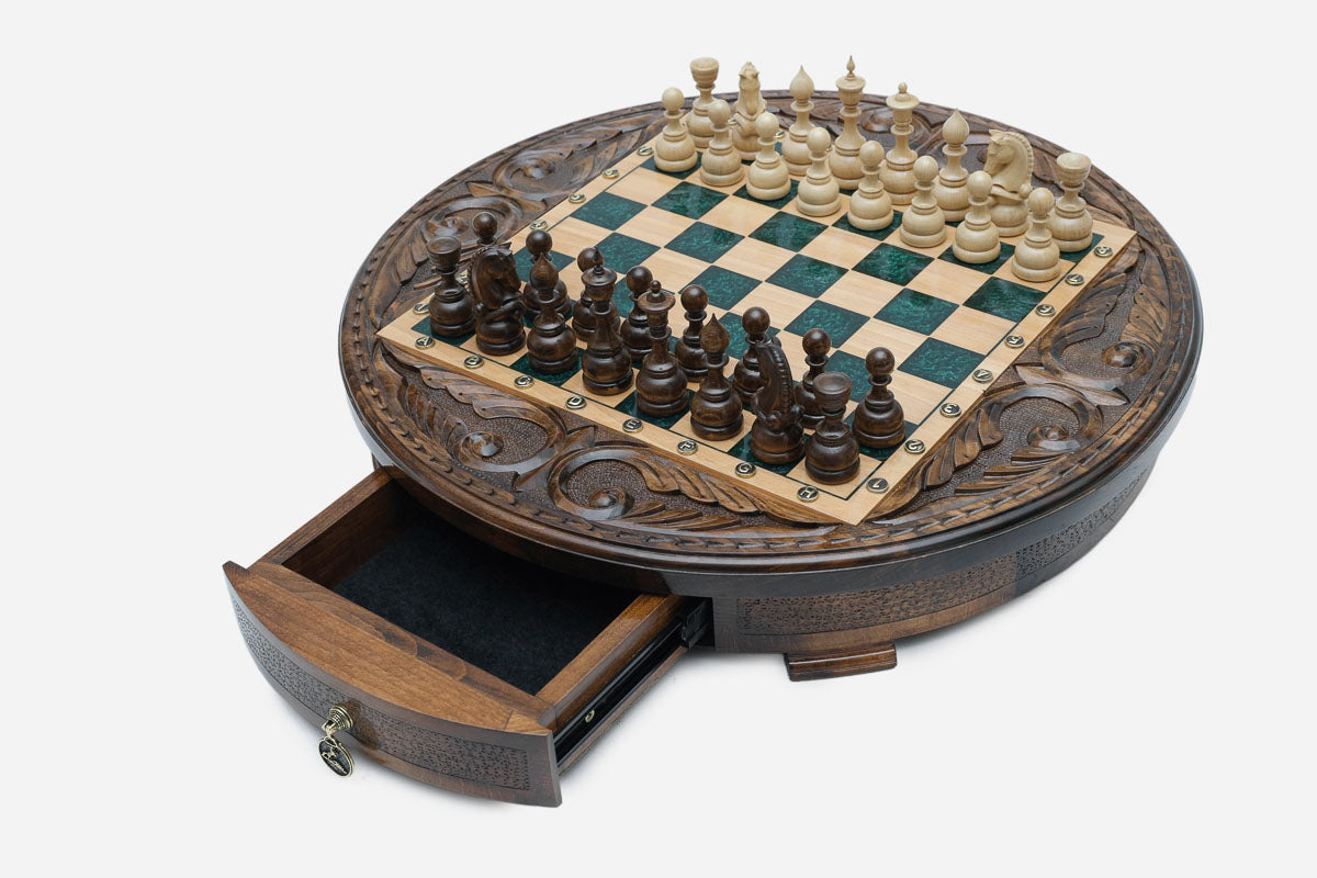 The round green epoxy chess set with its storage drawer open, showing the felt lining and brass pull