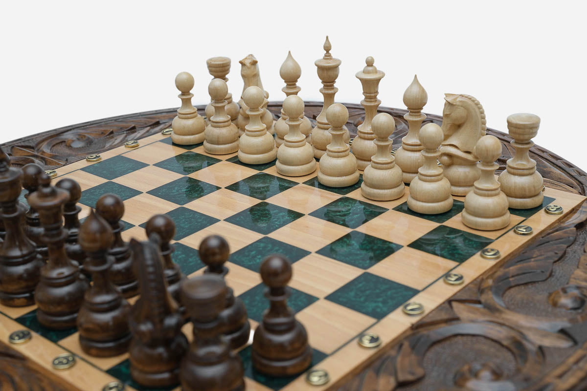 Close-up of the light natural-wood chess pieces on the glossy green epoxy squares