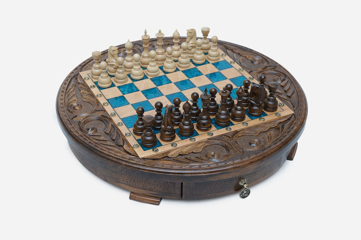 Full view of the round blue epoxy chess board with light and dark pieces in starting position