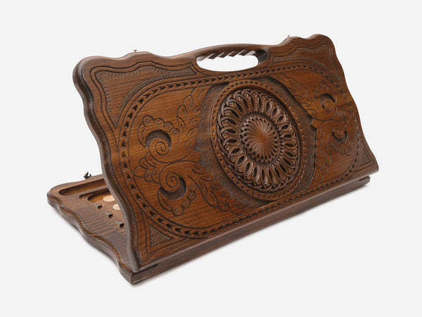 Carved Armenian backgammon board with a deep central ornament, floral carving and a cut-out carry handle, propped open