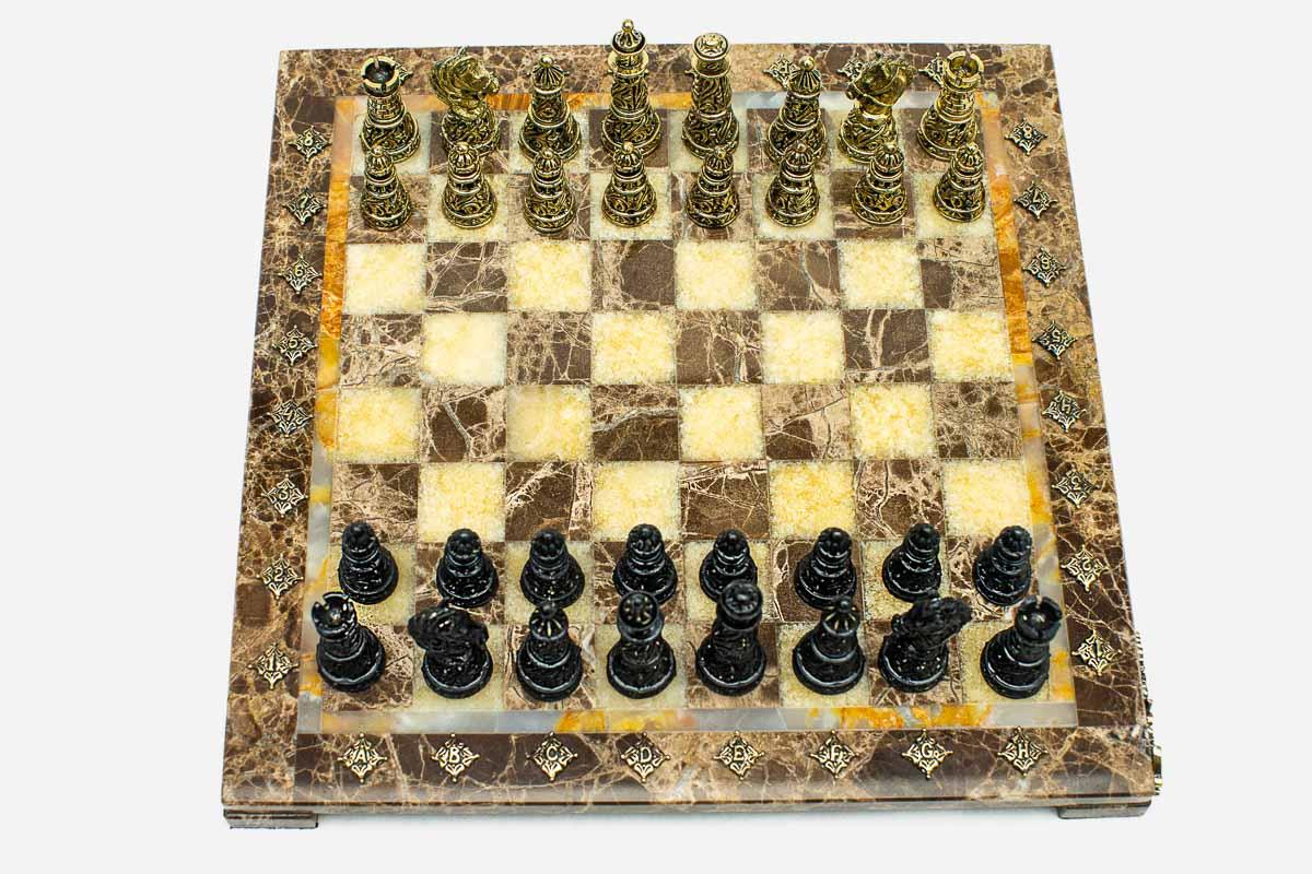 Marble and onyx chess set with brown marble and golden onyx squares and hand-cast bronze pieces arranged for play