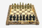 Angled view of the marble and onyx chess board with gold and dark bronze pieces set up for play