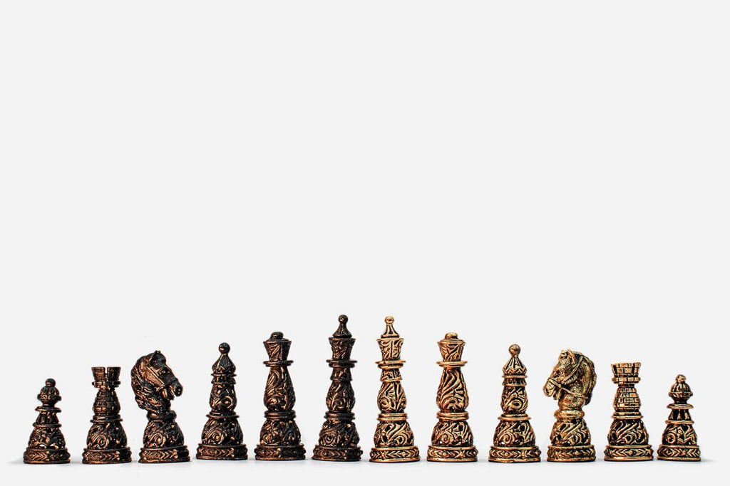Row of the intricately cast bronze chess pieces showing kings, queens, bishops, horse-head knights and rooks