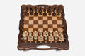 Luxury classic walnut chess set with a scalloped, hand-textured frame and turned pieces in starting position