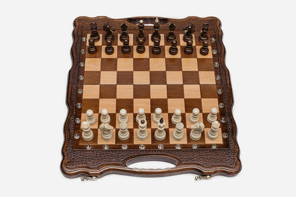 Luxury classic walnut chess set with a scalloped, hand-textured frame and turned pieces in starting position