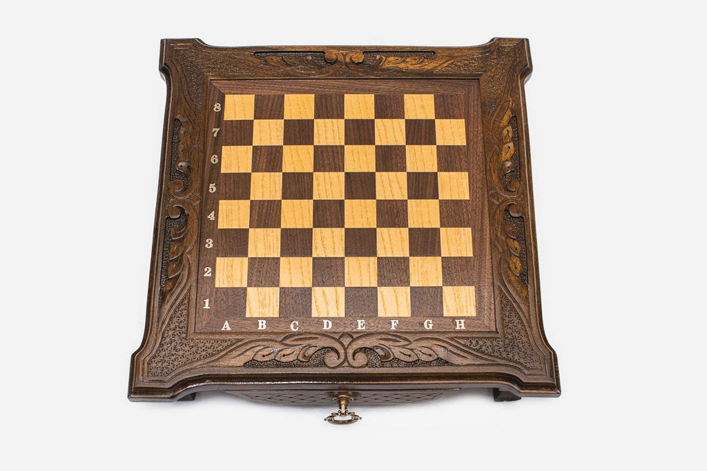 Top-down view of the empty compact dark walnut chess board with carved corners and inlaid surface