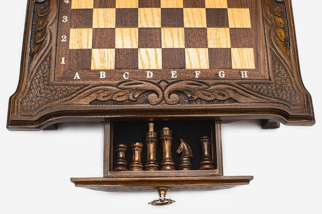 Close-up of the compact chess set's front storage drawer open, showing the dark chess pieces