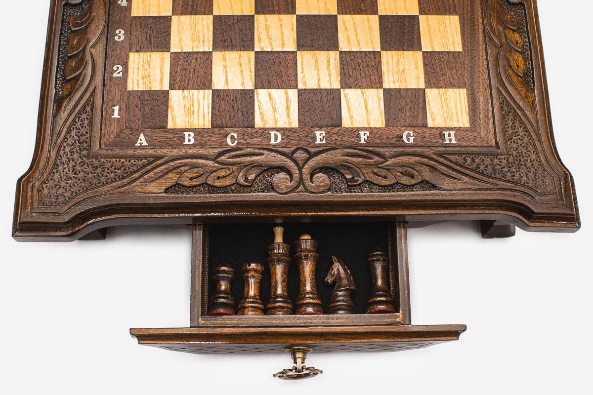 Close-up of the compact chess set's front storage drawer open, showing the dark chess pieces