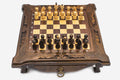 Compact dark walnut chess set with scroll-carved corners and wooden pieces set up on the inlaid board