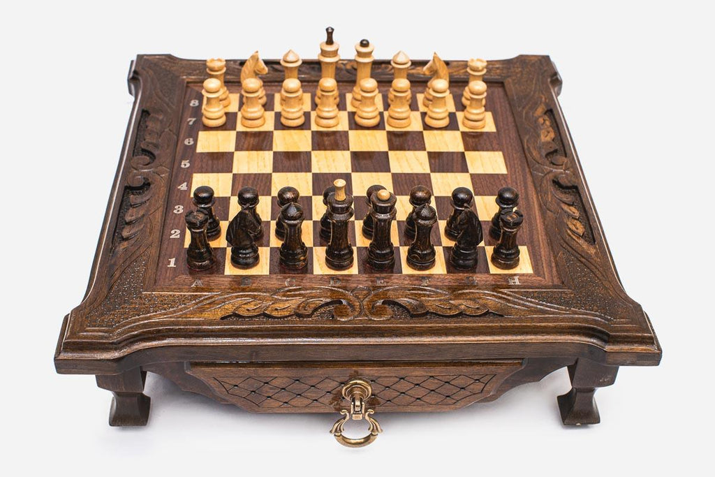 Compact dark walnut chess set shown from the front with pieces set up and a brass drawer ring