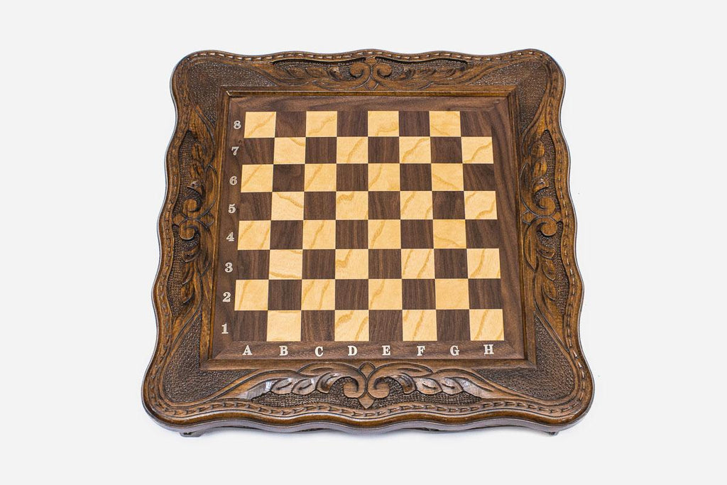 Top-down view of the empty compact chess board with carved corners and inlaid checkered surface