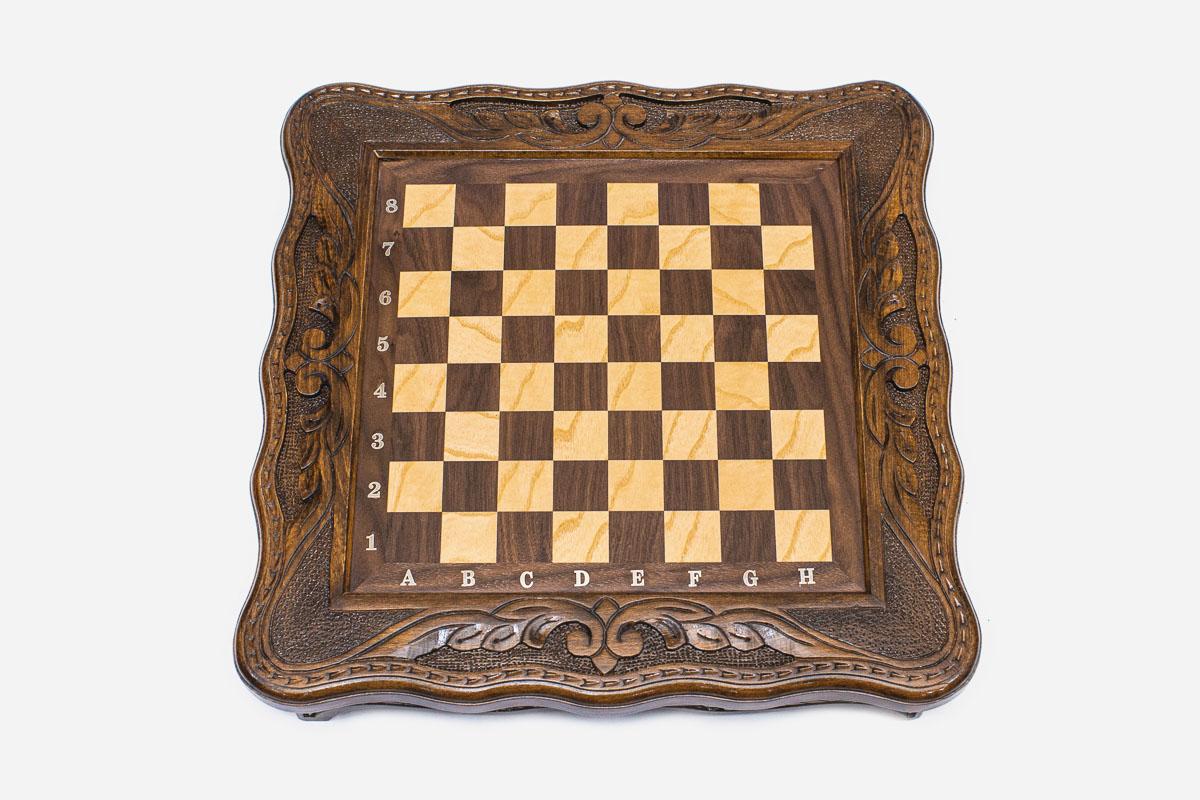 Top-down view of the empty compact chess board with carved corners and inlaid checkered surface