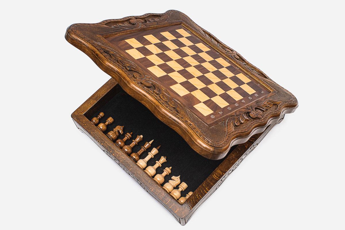 Compact chess set with the board top lifted, revealing the felt-lined storage compartment holding the pieces